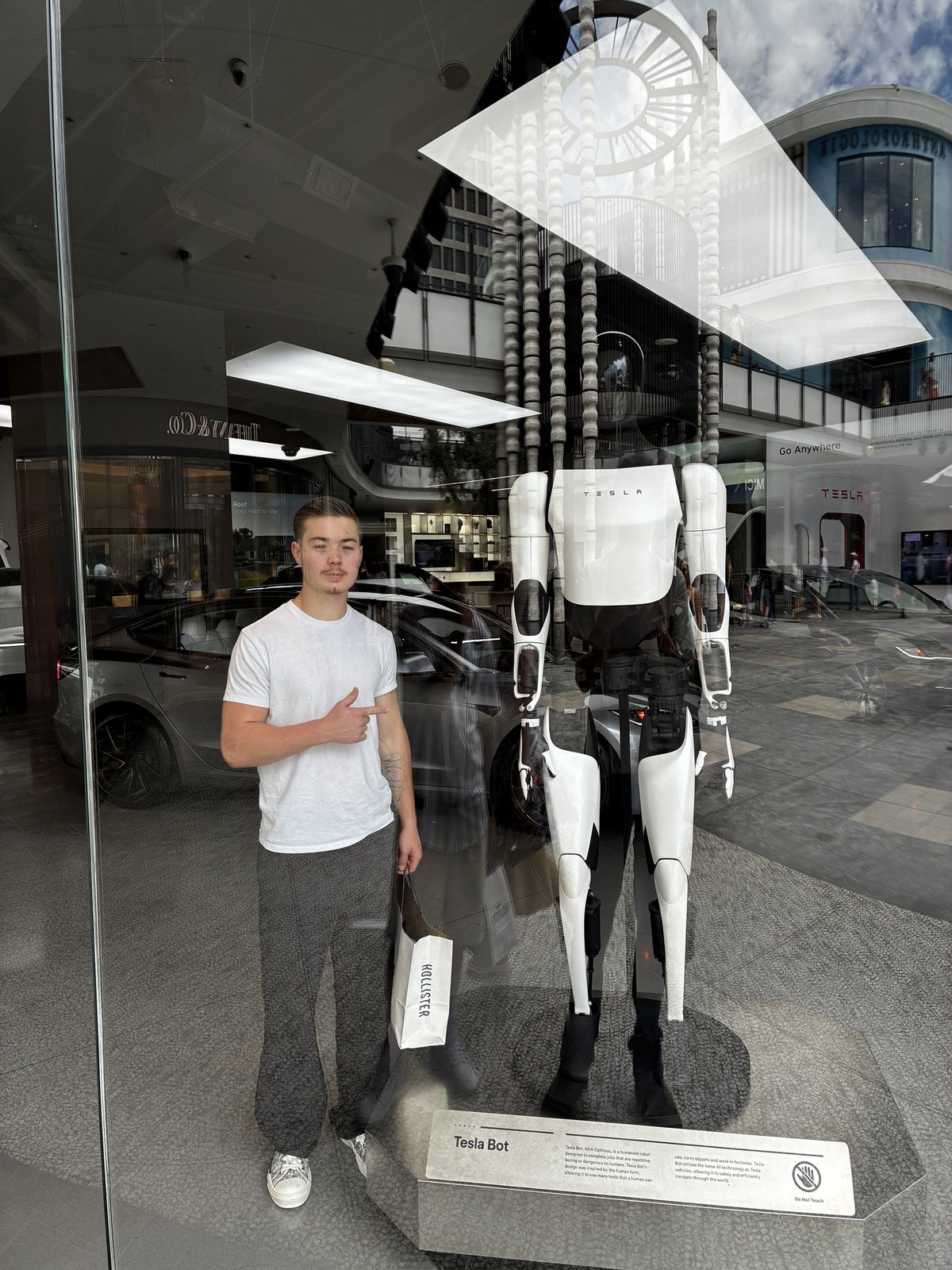 Everett Holt pointing at a Tesla Bot in a showroom window